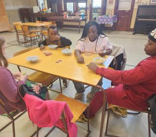 Four Youth play Uno and eat sitting around a table