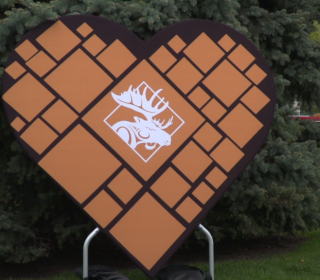 A large sign in the shape of a heart with a white moose icon in the middle