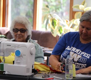 Two women sit at a craft table. 