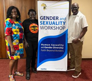 Three smiling adults stand near a poster that says "Faith Beyond Borders" and "Gender and Sexuality Workshop"