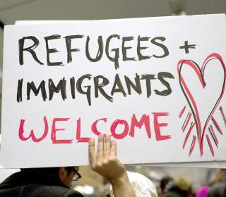 Person holding a sign that says "Refugees and Immigrants Welcome"