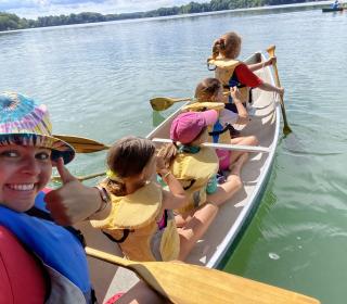 Children and an adult paddle a canoe