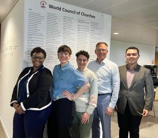A group of people pose in front of a wall that reads "World Council of Churches"