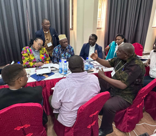 A group of African people sit around a long table in a board room having a discussion