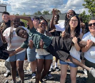 10 youth post for a photo energetically, with one being held across the middle by all