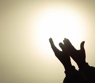 hands lifted in prayer toward light