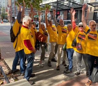 A group of people in yellow shirts in the streets raise their fists