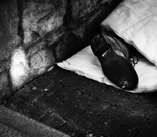 A man's foot peeks out of his blanket, as he sleeps on the street.