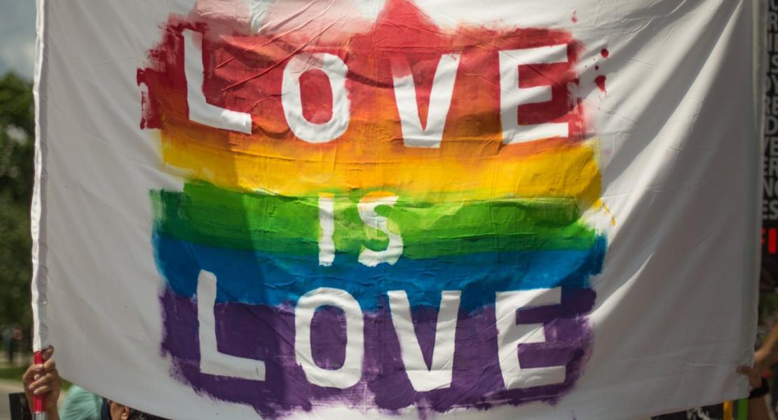 White banner with pride colours and the text "Love is Love" on it.