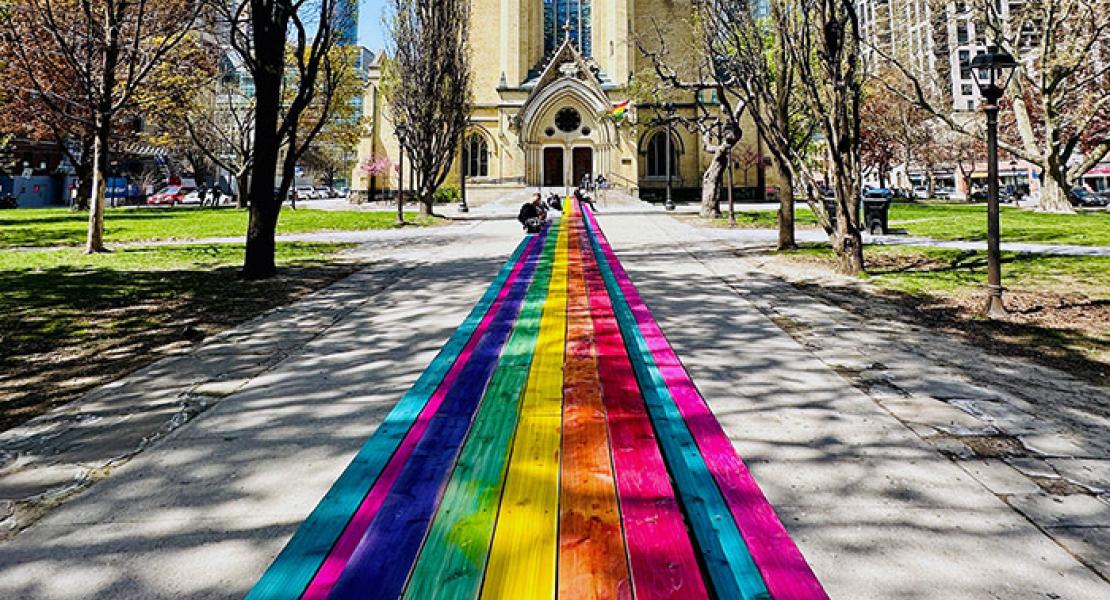 A rainbow coloured 100 foot table in front of the historic Metropolitan United Church Toronto