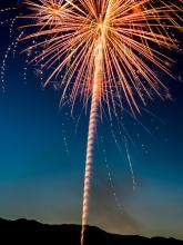 A firework exploding across the dark blue night sky