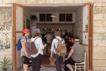 A group of young adult pilgrims from Canada gather in a doorway of a refugee-run cafe in Aida Refugee Camp.