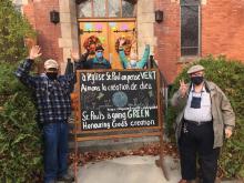 Members of St. Paul's United Church celebrate the "greening" of their church furnace on the steps of the church with banners and signs.