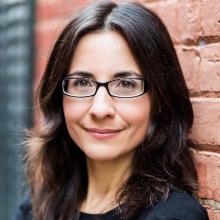 A headshot of the author, Julie McGonegal, a woman with long dark hair and rectangular glasses, smiling at the camera.