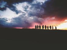 A Group of People Stand Silhouetted by the Setting Sun