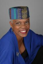 A picture of a Black woman wearing a blue kufi.