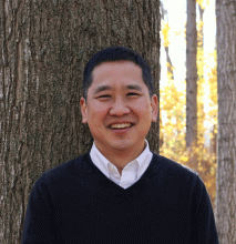 Kenji Marui, a man of Asian descent with a black sweater, with fall forest in the background