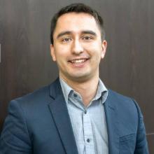 A portrait of Mitchell Anderson wearing a suit. He is a Dene man and lead minister at St. Paul’s United Church, Saskatoon