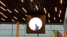 a large clock hanging from a lighted ceiling