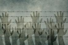 Silhouettes of hands against barbed wire in grey and white