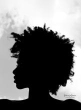 A silhouette head shot photo of Jonisha Lewinson, a young Black woman with free-flowing hair.