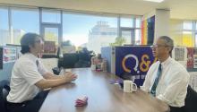 Two men talking together across a boardroom table in an office