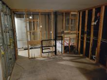 The interior of a house, stripped to the frames, with plumbing and electrical wires revealed.