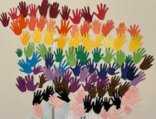 An artwork made of many handprints in rainbows on a wall