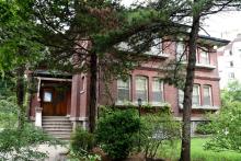 A large red-brick house behind trees