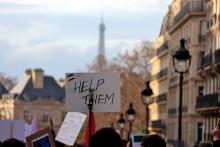 A sign with the words "Help them" is held up at a street protest