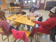 Four Youth play Uno and eat sitting around a table