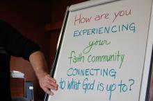 A flip chart sign asks the question, "How are you experiencing your faith community?"