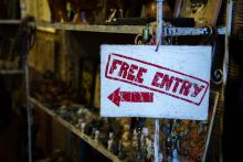 A sign in a store which says "Free Entry" and has an arrow pointing to the left.