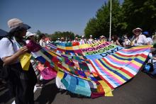 WomenCrossDMZ unfurl a colourful quilt during a march calling for peace in Korea/