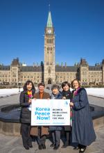 A group of five women pose in front of the tower at Parliament Hill in Ottawa on a brilliant cloudless day, where they advocated for peace in the Korean peninsula.