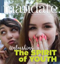 The cover of Mandate magazine from Winter 2019 shows the faces of two young women, a white woman (right) holds her hands with bright pink nails in front of her mouth; behind her to the left, a woman possibly a person of colour, makes amusing face.