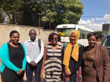 Four women and one man pose together in a Nairobi street. All are well dressed and workers for refugee assistance program.