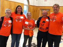 A group of five people about middle aged, each wearing an orange "Every Child Matters" t-shirt.