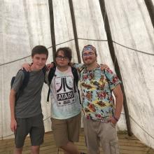Three young men from the GC43 Pilgrims group pose together in a tepee while learning about the First Nations in the Saskatchewan area.