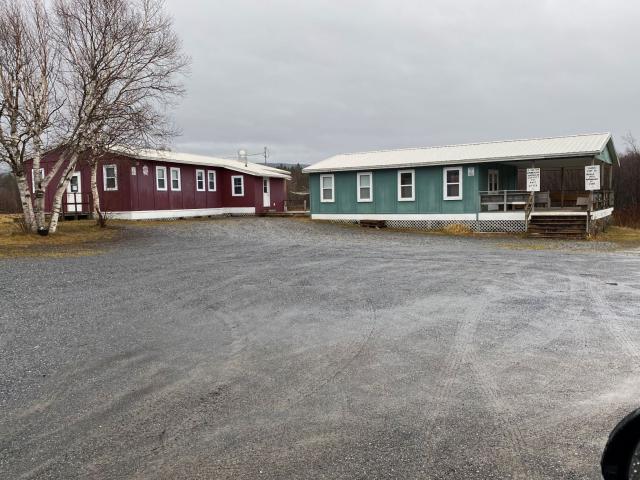 Two one-storey buildings at the end of a gravel road