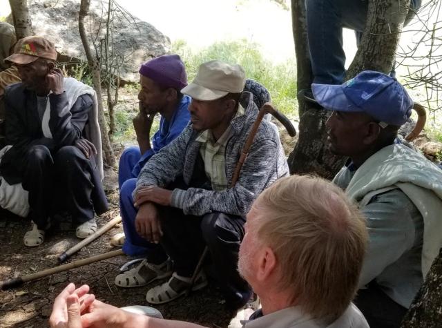 A group of men in Ethiopia sitting on the ground listening to someone