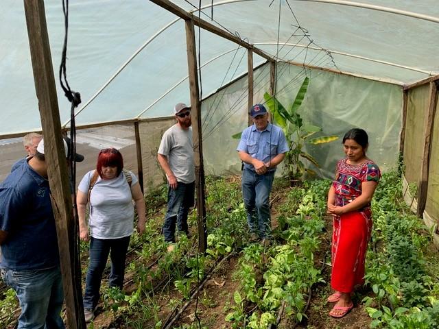 A young woman in the traditional dress of the women of Nebaj, Guatemala, shows a group of visitors the garden where she has applied new agricultural skills.