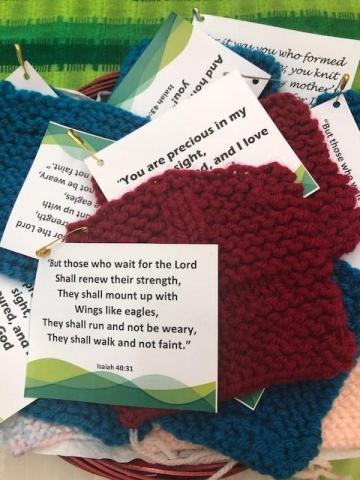 Image: Printed Bible verses, each pinned to a small knitted square, lying on a table in the GC43 chaplaincy room