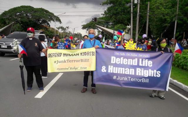 People on street hold up banners protesting human rights abuses in the Philippines