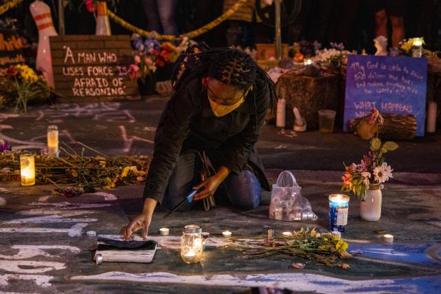 A Black person sets down a candle during a street vigil in the aftermath of the Chauvin trial.
