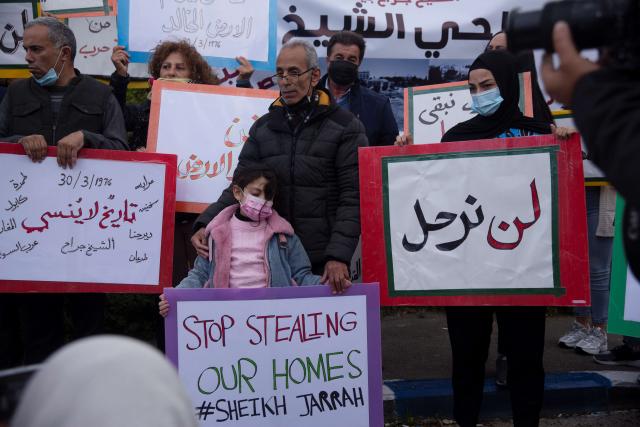 Palestinian people hold up signs protesting evictions in East Jerusalem