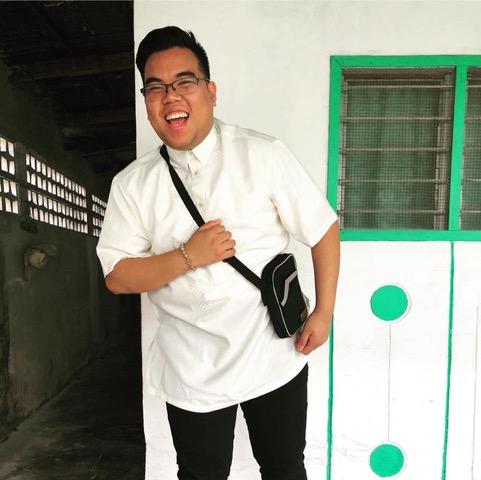 Klaus Simon Bondoc, a young Fillipino man with a brilliant smile, appears to be laughing and exclaiming while dressed in a buttoned-up white shirt.