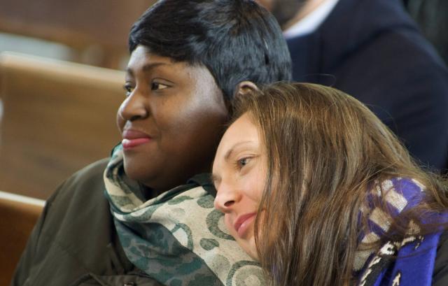 One woman rests her head on another woman's shoulder at a worship service