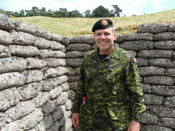 Padre Klotz in a camouflage uniform, poses in a trench at Vimy Ridge.