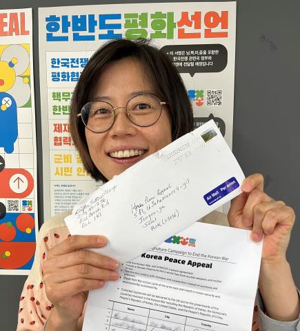 A woman holds up a signed petition and the envelope it was mailed in to Korea